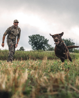 A hunter with his dog running.