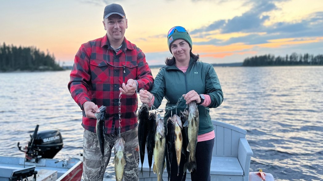 Un couple qui montre ses poissons devant un coucher de soleil