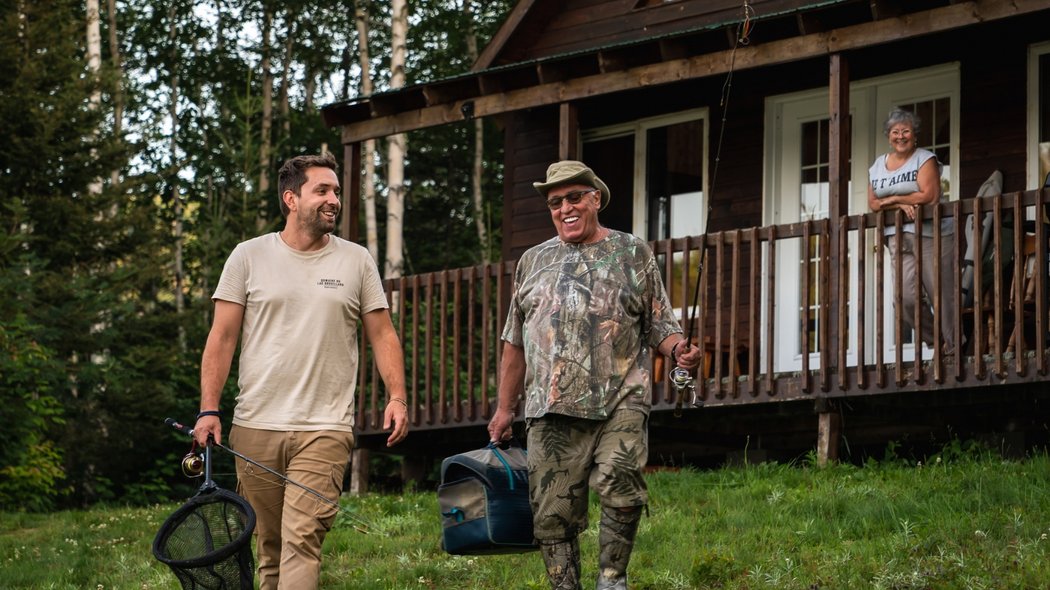 An outfitter and his client in front of a cottage