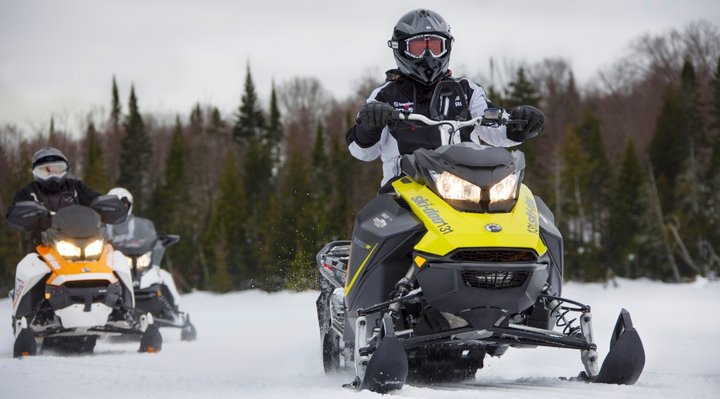 Deux motoneigistes sur un sentier en hiver 