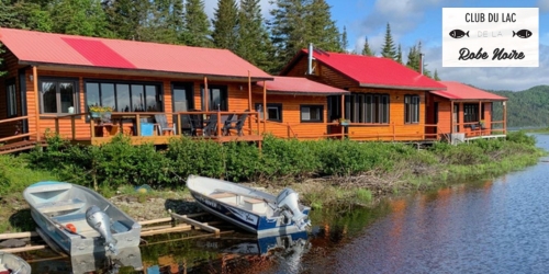 Chalets sur le bord de l'eau avec chaloupes et logo Club de la Robe Noire