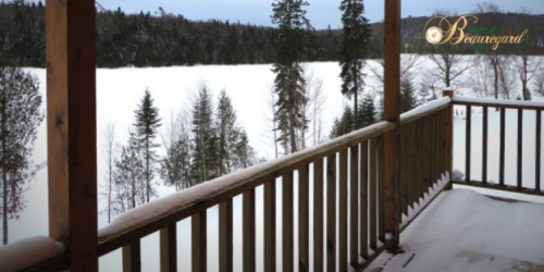 Vue d'un lac enneigé et de la forêt à partir d'une galerie en bois